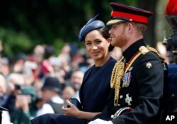 FILE - Britain's Meghan, the Duchess of Sussex and Prince Harry ride in a carriage to attend the annual Trooping the Colour Ceremony in London, June 8, 2019.
