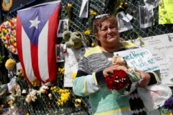 FILE - Maria Perdomo grieves by a makeshift memorial for the victims of the Surfside's Champlain Towers South condominium collapse in Miami, Florida, July 8, 2021.