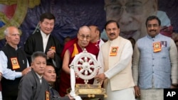 Pemimpin spiritual Tibet, Dalai Lama, memberikan kenang-kenangan ke Wakil Menteri Kebudayaan Mahesh Sharma, dua dari kanan, saat dia tiba untuk menghadiri acara peringat 60 tahun pengasingan Dalai Lama di Dharmsala, India, 31 Maret 2018.