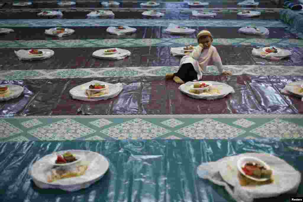 Seorang anak laki-laki menyaksikan orang-orang mendistribusikan makanan menjelang berbuka puasa di sebuah masjid di Singapura (29/6).&nbsp;(Reuters/Edgar Su)