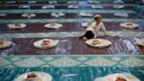 A boy watches helpers distribute food as he waits to break fast with devotees on the first day of Ramadan at a mosque in Singapore.
