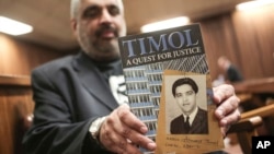 Imtiaz Cajee, nephew of Ahmed Timol, poses with his book "Timol, A Quest for Justice" in the North Gauteng High court in Pretoria, South Africa, Thursday, Aug. 24, 2017 after the court heard the final arguments in the inquest into the death of anti-apartheid activist, Ahmed Timol (portrait on cover). Police say Timol died when he leapt from the 10th floor of the then John Vorster Square police station in Johannesburg in 1971.