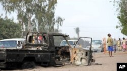 People drive past a burnt-out truck in Maputo, Mozambique, 04 Sep 2010