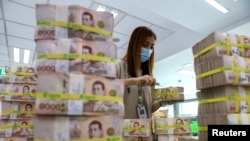 FILE - A bank employee gathers Thai baht notes at a Kasikornbank in Bangkok, Thailand, Jan. 26, 2023.