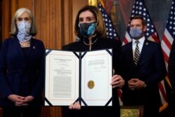 U.S. House Speaker Nancy Pelosi displays the signed article of impeachment against President Donald Trump in an engrossment ceremony before transmission to the Senate for trial, at the Capitol in Washington, Jan. 13, 2021.