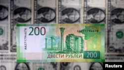 FILE PHOTO: Illustration shows a Russian rouble banknote placed on U.S. dollar banknotes
