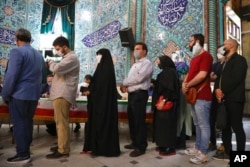 Voters queue at a polling station during the presidential elections in Tehran, Iran, June 18, 2021.
