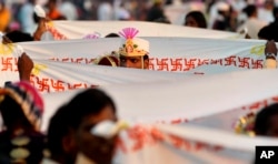 A groom stands behind a sheet bearing the Hindu swastika during a ritual at a mass wedding ceremony in Virar, on the outskirts of Mumbai, India, Sunday, Jan. 29, 2012. (AP Photo/Rajanish Kakade)