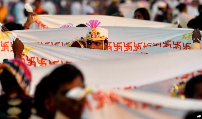 A groom stands behind a sheet bearing the Hindu swastika during a ritual at a mass wedding ceremony in Virar, on the outskirts of Mumbai, India, Sunday, Jan. 29, 2012. (AP Photo/Rajanish Kakade)