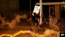 A protester stands in the street after police fired tear gas to disperse a crowd Sunday, Aug. 17, 2014, during a protest for Michael Brown, who was killed by a police officer in Ferguson, Missouri.