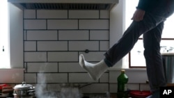 Jorge Sanhueza-Lyon stands on his kitchen counter to warm his feet over his gas stove in Austin, Texas, Feb. 16, 2021.