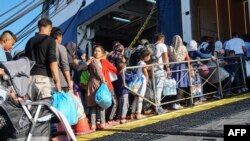 Refugees and migrants board a ferry on the island of Lesbos to be transferred to the port of Piraeus, Oct. 6, 2019. 