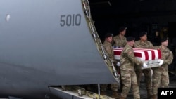 在多佛空军基地举行的肃穆的仪式上，美国陆军抬灵柩小队成员把运输在约旦因无人机袭击而丧生的美国陆军中士杰罗姆·里弗斯遗体的灵柩抬下飞机。(2024年2月2日)