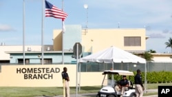 Security guards stand outside a former Job Corps site that now houses child immigrants, June 18, 2018, in Homestead, Fla. 