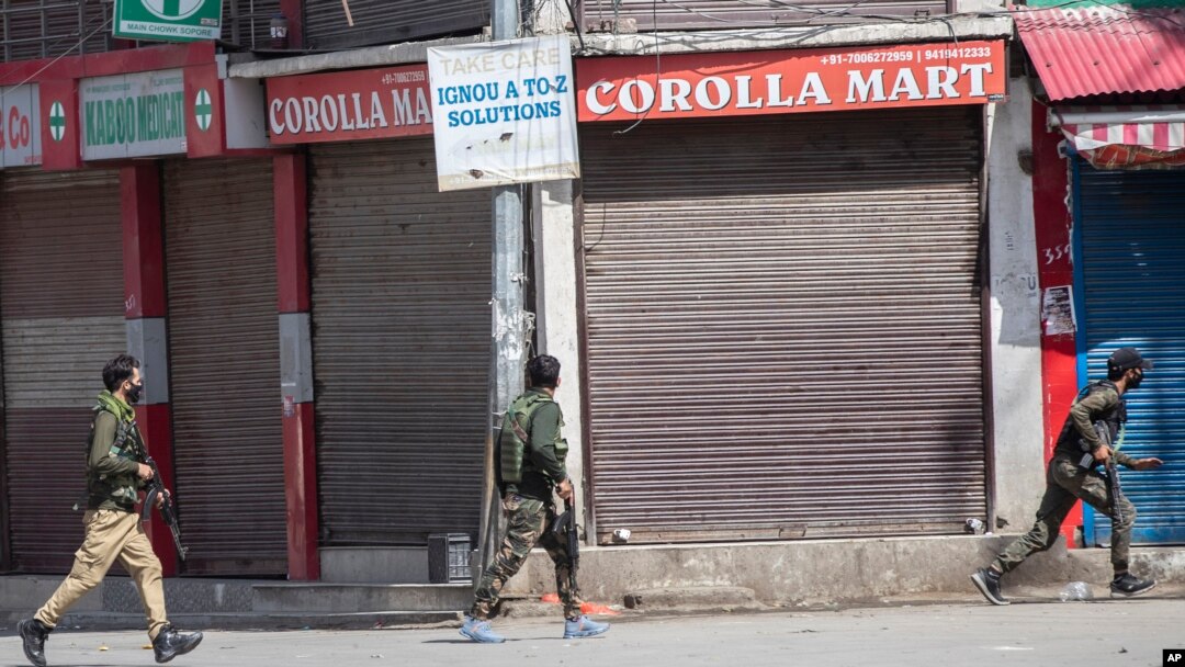 Polisi berlarian di dekat lokasi baku tembak di Sopore, 55 kilometer utara Srinagar, Kashmir yang dikuasai India, Sabtu, 12 Juni 2021. (AP/Mukhtar Khan)