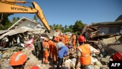 Para petugas penyelamat mencari korban-korban di bawah puing-puing di Desa Sigar Penjalin, utara Lombok, di Nusa Tenggara Barat, 8 Agustus 2018, tiga hari setelah gempa kuat mengguncang wilayah tersebut.