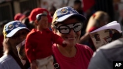 Una simpatizante del chavismo sonríe durante una marcha oficialista luciendo unas gafas con los ojos del expresidente Hugo Chávez, en Caracas, en julio de 2023.