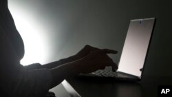 FILE - A Dec. 12, 2016, photo illustration shows a person typing on a laptop, in Miami, Florida. A new survey found that about one in four women that have been queried in eight different countries had experienced online abuse or harassment.