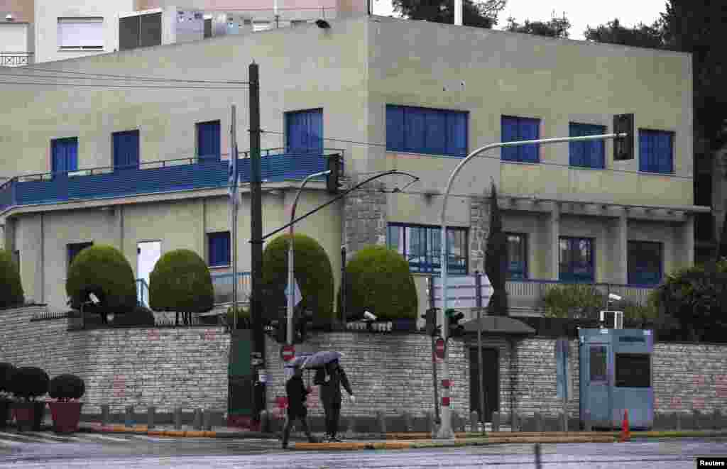 Two forensics officers look for evidence in front of the Israeli embassy after unidentified assailants opened fire on the embassy in Athens, Dec. 12, 2014.