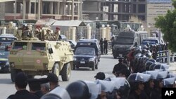 Egyptian policemen line the street as an armored army vehicle guards a convoy carrying former Egyptian interior minister Habib el-Adly and his aides, as they arrive at the court in Cairo, May 21, 2011