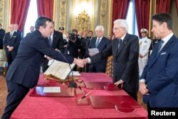 Vincenzo Amendola, left, shakes hands with Italian President Sergio Mattarella as he is sworn in as Italy's European affairs minister during a ceremony in Rome, Sept. 5, 2019.