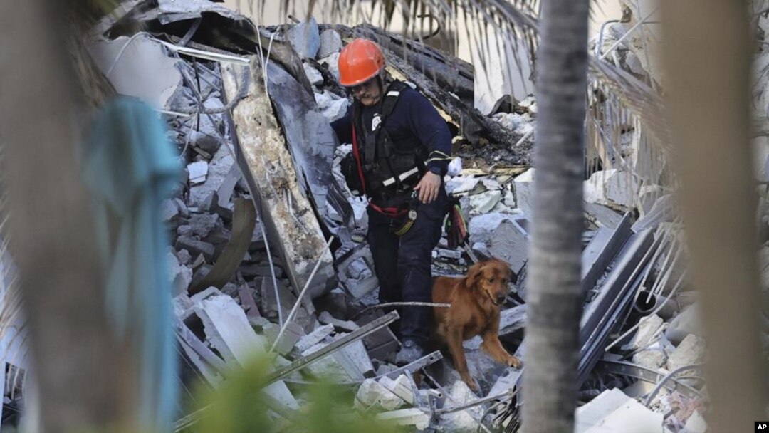 Petugas penyelamat mencari korban di antara reruntuhan gedung kondominium "Champlain Towers South Condo" di Surfside, Miami, Florida Kamis (24/6). 