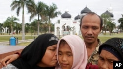 Jamaliah (kiri) mencium anak perempuannya Raudhatul Jannah, 14, bersama sang ayah Septi Rangkuti dan nenek Sarwani di masjid Baiturrahman di Banda Aceh 8 Agustus 2014.