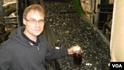 CEO John Bordynuik with a jar of fuel produced from waste plastic in JBI’s factory in Niagara Falls, New York. (VOA/D. Robison) 