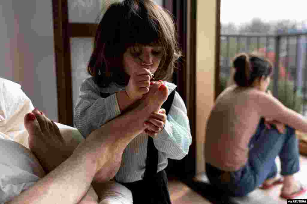 Schoolteacher Marzio Toniolo, 35, takes a picture of his 2-year-old daughter, Bianca, painting his toenails at their home during the coronavirus lockdown in San Fiorano, Italy.
