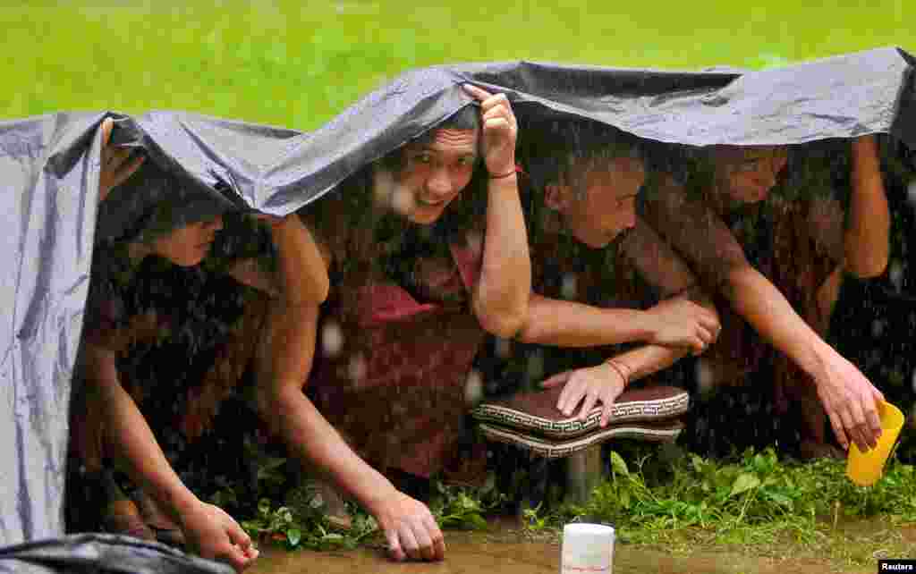 Buddhist monks take shelter to protect themselves from the rain, as they attend the birthday celebrations of the Tibetan spiritual leader the Dalai Lama (not pictured) at Drepung Loseling Monastery in Mundgod, in the southern state of Karnataka, India.