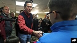 Republican presidential candidate former Pennsylvania Senator Rick Santorum reaches to greet children during a campaign stop in Brentwood, New Hampshire, January 4, 2012.