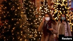 FILE - Women, wearing protective face masks, walk past illuminated Christmas trees in a street in Paris, France, Nov. 12, 2020.