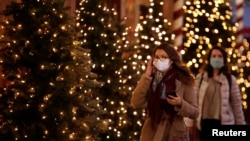 FILE - Women, wearing protective face masks, walk past illuminated Christmas trees in a street in Paris, France, Nov. 12, 2020.