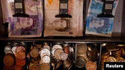 FILE - Pound notes and coins are seen inside a cash register in Manchester, Britain, Sept. 6, 2017. Britain's exit from the European Union's customs union could cost traders dearly.