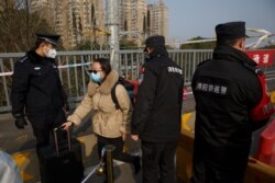A woman who arrived from Hubei province is permitted through a checkpoint at the Jiujiang Yangtze River Bridge into Jiujiang, Jiangxi province, China, as the country is hit by an outbreak of a new coronavirus, Jan. 31, 2020.