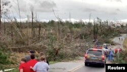 Warga setempat mengamati pembersihan puing-puing di sepanjang jalan pasca tornado di Beauregard, Alabama, AS dalam 3 Maret 2019. (Foto: videograb/Scott Fillmer via Reuters)