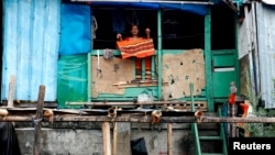 Seorang perempuan lansia berdiri di rumah gubuknya di tengah pandemi Covid-19 di Jakarta, 4 Agustus 2020. (REUTERS / Ajeng Dinar Ulfiana).