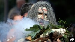 FILE - An Aboriginal man performs a smoking ceremony as protesters gather in Sydney, June 6, 2020, to support people in the US demonstrating over the death of George Floyd.