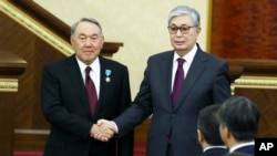 FILE - Kazakhstan's interim president Kassym-Jomart Tokayev, right, and outgoing Kazakh President Nursultan Nazarbayev shake hands after an inauguration ceremony in Astana, Kazakhstan, March 20, 2019.