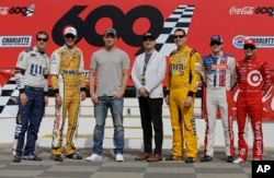FILE - Actor Channing Tatum, third from left, and director Steven Soderbergh, center, pose for a photo with NASCAR drivers, from left to right, Brad Keselowski, Joey Logano, Kyle Busch, Ryan Blaney and Kyle Larson before the NASCAR Cup series auto race at Charlotte Motor Speedway in Concord, N.C., May 28, 2017.