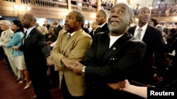 Pendeta Richard Harkness berpegangan tangan dengan pendeta Jack Lewin (dua dari kanan) saat para hadirin menyanyikan lagu pujian dan doa bersama, di gereja Morris Brown AME, Charleston, South Carolina (18/6).