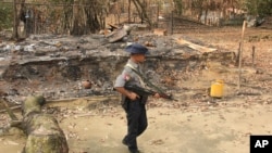 រូបឯកសារ៖ មន្ត្រី​សន្តិសុខ​មីយ៉ាន់ម៉ា​ដើរ​ក្បែរ​ផ្ទះរបស់​ជន​រ៉ូហ៊ីងយ៉ា ដែល​ត្រូវ​បាន​ដុត​កម្ទេច​ នៅ​ភូមិ Ka Nyin Tan នៅ​ជាយ​ក្រុង​ Maungdaw ស្ថិត​នៅ​រដ្ឋ​ Rakhine ភាគ​ខាង​ជើង នៃ​ប្រទេស​មីយ៉ាន់ម៉ា កាល​ពី​ខែ​សីហា ២០១៧។
