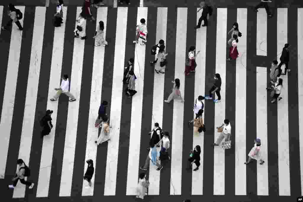 People wearing protective masks to help curb the spread of the coronavirus walk along a pedestrian crossing in Tokyo, Japan.