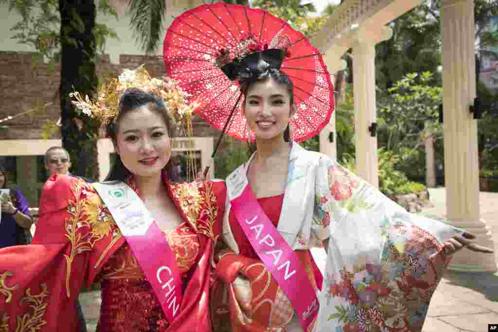 دو دختر فینالیست در مسابقات دختر شایسته مالزی با لباس های محلی برای عکاسان ژست می&zwnj;گیرند.