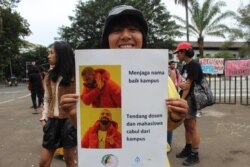 Seorang peserta aksi IWD 2020 menunjukkan poster dalam aksi di Bandung, Minggu, 8 Maret 2020. (Foto: Rio Tuasikal/VOA)