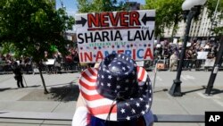 اعتراض کنندگان شعار های را بلند کردند که در نوشته بود: هیچگاهی شریعت اسلامی را در امریکا نمی خواهیم