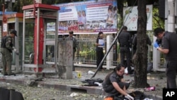 Police and forensic experts investigate the site where a man was injured when a bomb he was carrying exploded, in central Bangkok, Feb. 14, 2012