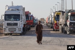 Trucks with humanitarian aid wait to enter the Palestinian side of Rafah on the Egyptian border with the Gaza Strip, Dec. 11, 2023.
