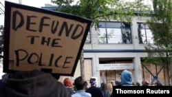 Un manifestante carga una pancarta que reza "Retiren fondos a la policía" durante una reciente protesta en Seattle. 
