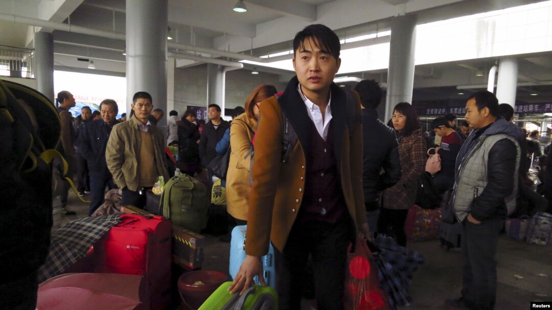 Para pekerja migran dengan koper dan bagasinya antre di stasiun kereta api di Dongguan, China bagian selatan (1/2). (Reuters/James Pomfret)
